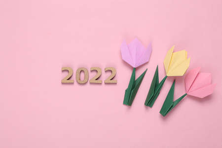 Origami colored tulips, 2022 on pink background. spring 2022 symbol