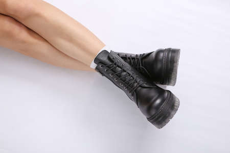 Female legs in trendy leather black boots on a white background