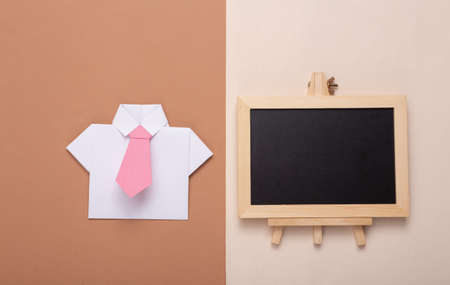 Mini blank chalk board with copy space and paper shirt with tie on brown beige background. business training conceptの写真素材