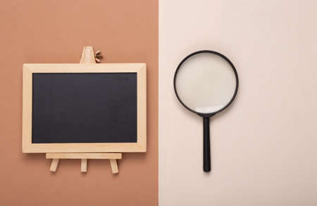 Magnifier and Mini blackboard on brown beige background. Empty, blank chalkboard with copy space. Business, education, learning concept.の写真素材