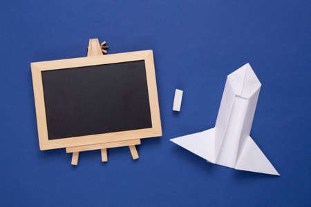 Paper rocket and empty chalk board on blue background. Startup, education conceptの写真素材