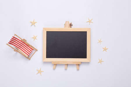 beach holidays. Mini deck chair, starfishes and empty chalk board on white background. copy space