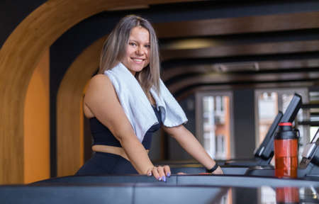 Healthy cheerful fitness woman in sportswear on a treadmill in a gymの写真素材