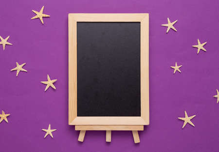 Empty chalk board with starfish on a purple background. vacation on the beach conceptの写真素材