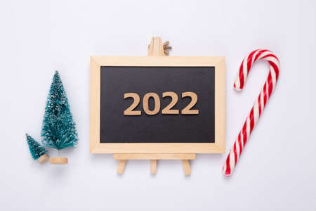 Mini blackboard with Christmas tree, candy on white background. Chalkboard with 2022. New year, Christmas still lifeの写真素材