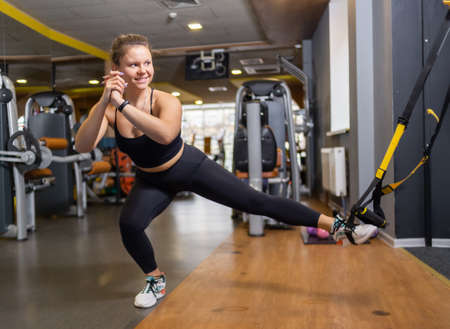 Young fit woman trains with trx resistance system in a modern gym. healthy lifestyleの写真素材