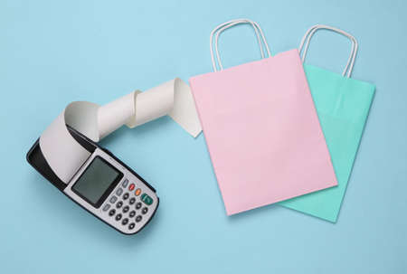 Payment terminal with shopping packages on a blue background. shopping, payment for purchases