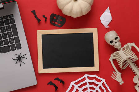 Laptop, Mini blank chalk board with copy space and halloween decor on red background. Trick or treat. flat layの写真素材