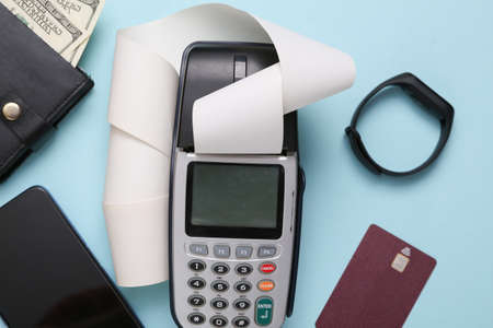 Payment terminal with smartphone, smart bracelet, purse and bank card on blue background....
