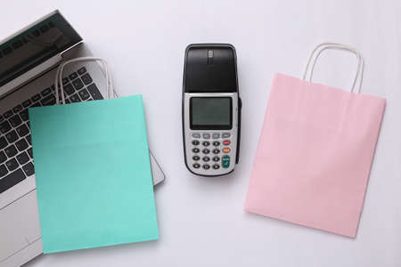 Payment terminal, shopping bags and laptop on white background. Payment for purchases. online shopping. top viewの写真素材