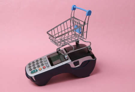 Payment terminal with empty shopping trolley on pink background.の写真素材