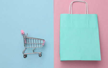 Shopping bag with shopping trolley on pink blue background. sale. top viewの写真素材