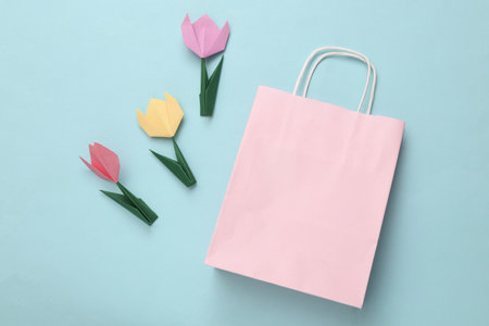 Shopping bag and origami tulips on a blue background. spring sale. top viewの写真素材