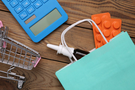 Shopping bag with medicines, shopping trolley and calculator on wooden table. top viewの写真素材