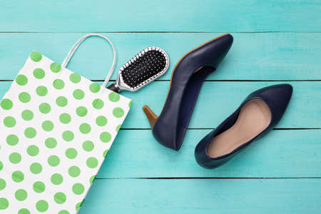 Paper polka dots shopping bag with shoes and hair brush on blue wooden background. top viewの写真素材