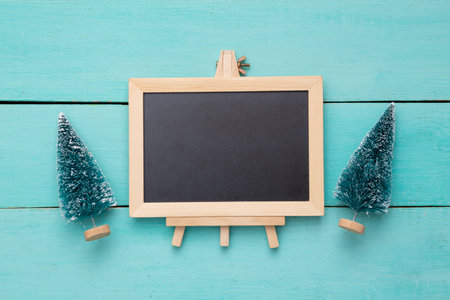 Toy Christmas trees and Blank mini chalk board on a light blue wooden background. copy spaceの写真素材