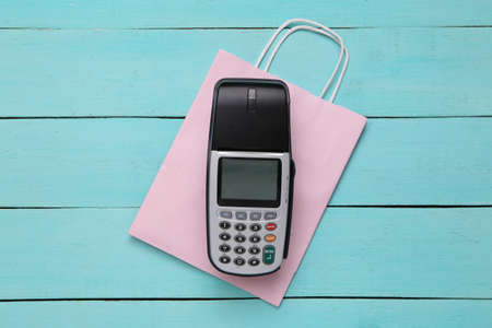 Payment terminal with shopping bag on blue wooden table. shopping concept. top viewの写真素材