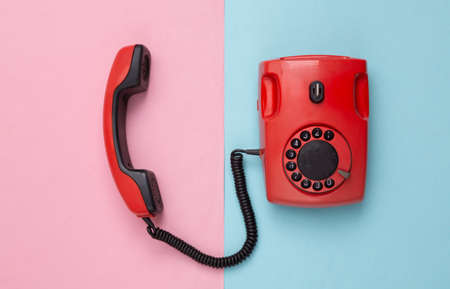 Retro red old fashioned rotary phone on pink blue background. top viewの写真素材