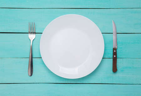 Plate with fork and knife on blue wooden background. top view