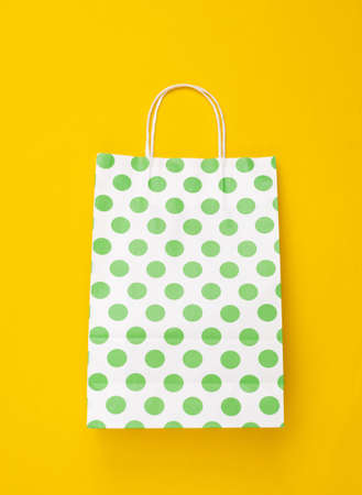 Paper shopping bag with polka dots on yellow background