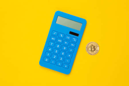 Calculator and bitcoin on yellow background. top viewの写真素材