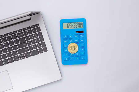 Calculator, laptop and bitcoin on gray background. top viewの写真素材