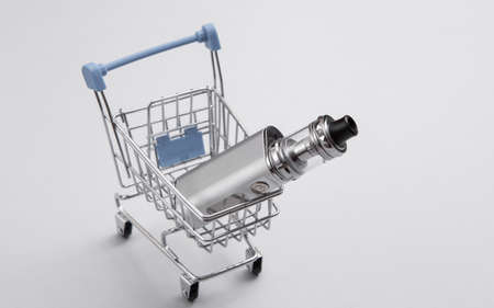 Vaping device in mini shopping cart on gray background