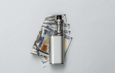 Vaping device and dollar bills on a gray background