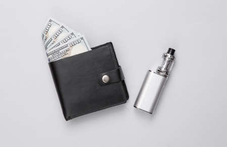 Vaping device and wallet with money on a gray background. smoking costsの写真素材