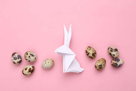 Easter composition. Origami Easter bunny and quail eggs on a pink pastel background. top viewの写真素材