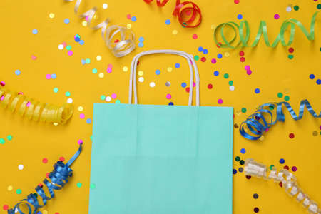 Shopping bag with Colored streamer and confetti on yellow background. shopping dayの写真素材