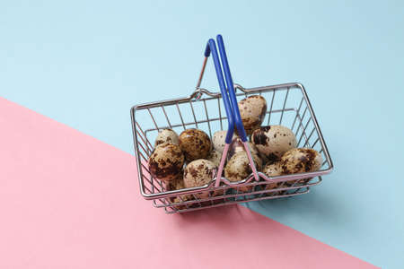 Shopping basket with quail eggs on pink blue backgroundの写真素材