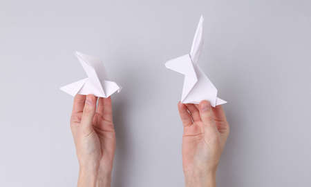 Hands hold hand made origami rabbit and dove on gray backgroundの写真素材