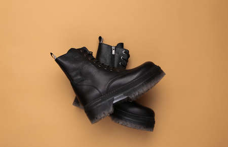 Stylish leather boots with high soles on a beige background