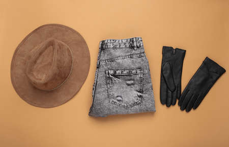 Stylish leather gloves, jeans and hat on a beige background. Women's autumn accessories. top view. flat layの写真素材