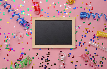 Empty blackboard with Colored streamer and confetti on a pink background. Holiday, birthday backgroundの写真素材