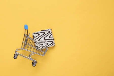 Shopping trolley with delicious cake with frosting on a yellow backgroundの写真素材