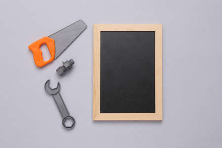 Toy tools and empty chalk board on gray background. repair concept. copy spaceの写真素材