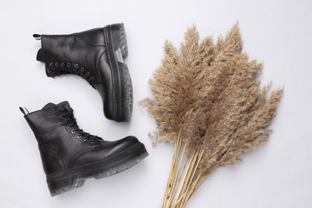 Autumn fashion composition of leather boots and Reeds foliage branches bouquet on a beige background. top viewの写真素材