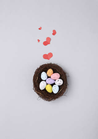 Nest with colored quail eggs and hearts on gray background. Easter composition. top viewの写真素材