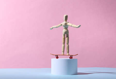 Wooden puppet with a skateboard on the stand. Blue-pink background. minimalismの写真素材