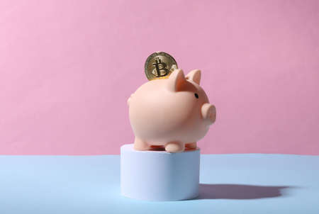 Piggy bank with bitcoin on stand. blue pink pastel backgroundの写真素材
