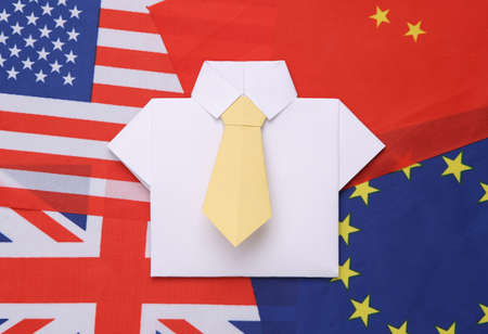 Origami shirt with tie on the background of many flags. Politics or business conceptの写真素材