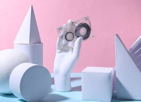 The mannequin's hand holds audio cassette and geometric shapes on pink blue background. fashion showcase. 80s concept art.の写真素材