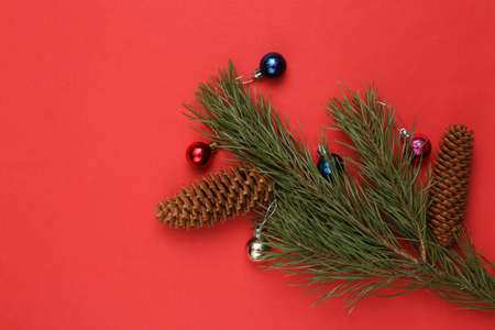 Pine branch with Christmas decorations balls and cones on a red background. Christmas, new year backgroundの写真素材