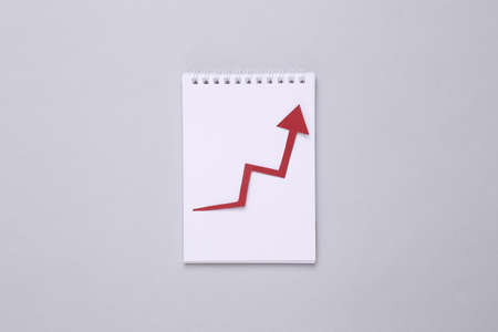 Notepad with growth arrow on gray background. business conceptの写真素材