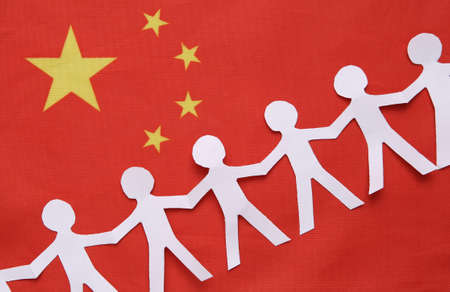 Chain of paper-cut people against the background of China flag. unity concept. Together we are strongerの写真素材