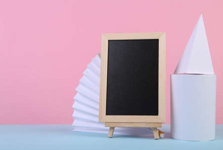 Empty chalk board and geometric shapes on blue pink pastel background. Abstract background, concept art, minimalism. school composition. copy spaceの写真素材
