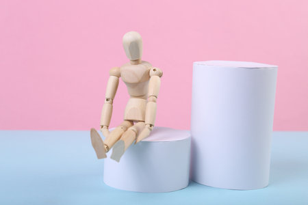 Wooden puppet on a blue-pink background with geometric shapes.の写真素材