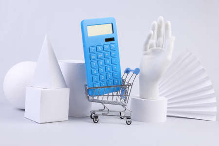 Shopping trolley with calculator and geometric shapes on a white background. concept artの写真素材